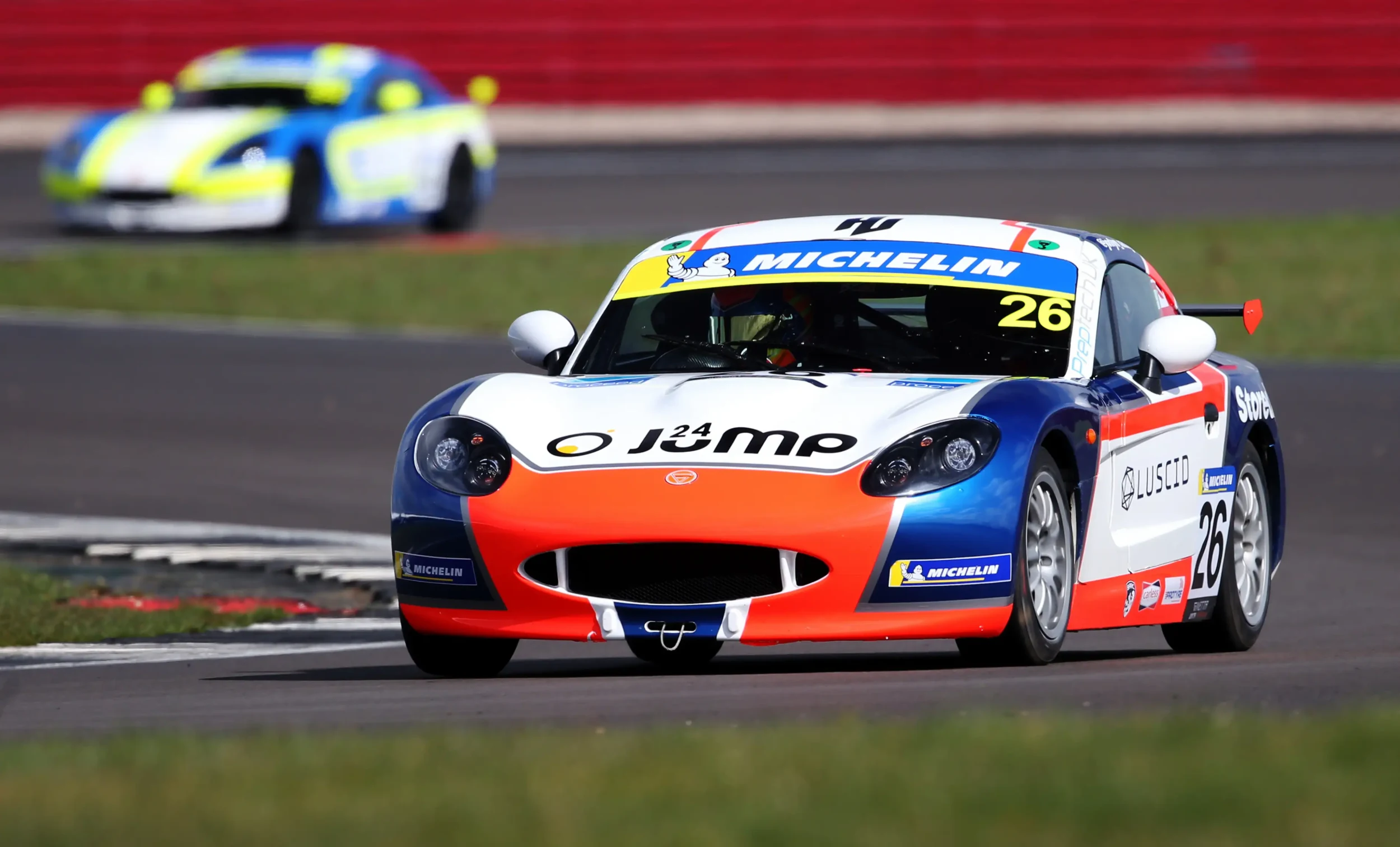 A Ginetta racing through a chicane on a motor racing circuit