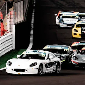 Ginetta racing cars entering a corner on a circuit in close competition